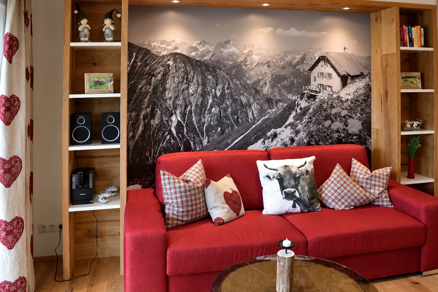 Gerade ausgerichteter Wohnbereich der Alpenfirn Suite mit rotem Sofa und alpinem Wandmotiv